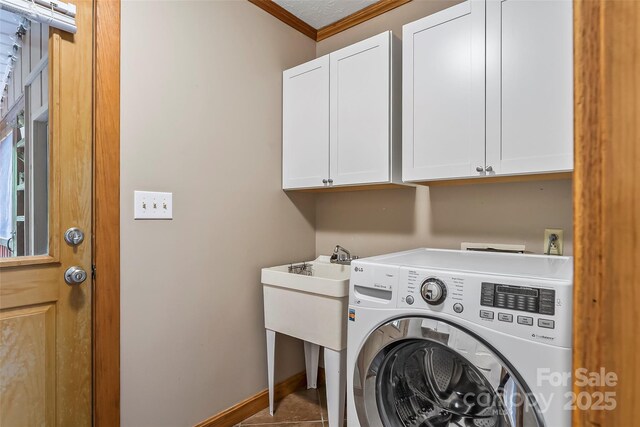 clothes washing area with tile patterned floors, washer / dryer, crown molding, a textured ceiling, and cabinets