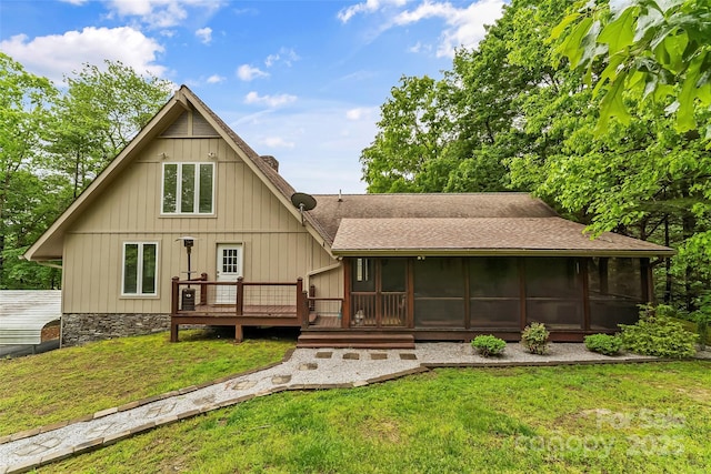 rear view of house with a deck, a sunroom, and a yard