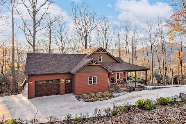 rustic home featuring a porch, driveway, a shingled roof, and a garage