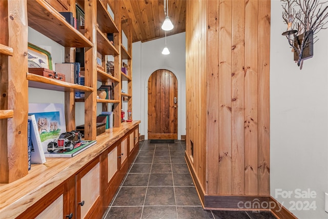 corridor featuring dark tile floors, wooden ceiling, and vaulted ceiling