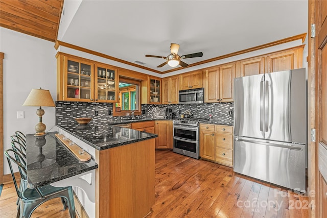 kitchen with kitchen peninsula, backsplash, light wood-type flooring, and stainless steel appliances