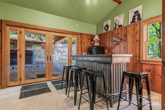 bar featuring carpet, wood walls, lofted ceiling, and black fridge