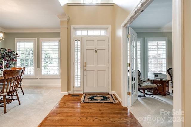 entryway featuring wood-type flooring, a wealth of natural light, and ornamental molding