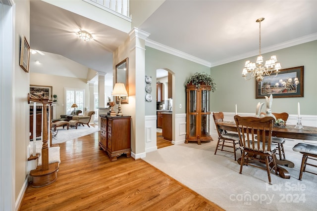 dining space with crown molding, an inviting chandelier, decorative columns, and light hardwood / wood-style floors