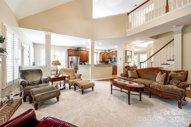 carpeted living room featuring high vaulted ceiling, a wealth of natural light, and decorative columns