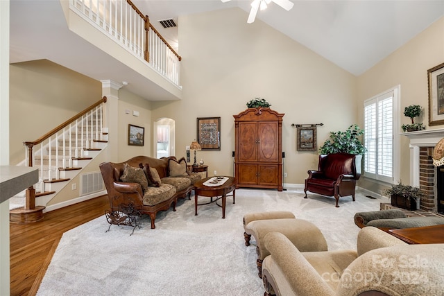 living room featuring high vaulted ceiling, ceiling fan, wood-type flooring, and a fireplace