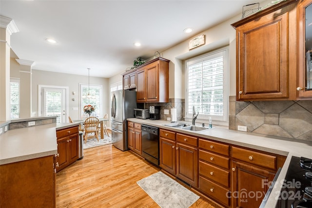 kitchen with light wood-type flooring, black appliances, hanging light fixtures, and plenty of natural light