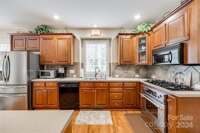 kitchen featuring black appliances, sink, decorative backsplash, and light hardwood / wood-style floors