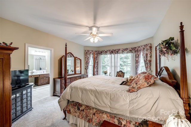 bedroom with ceiling fan, light carpet, and ensuite bath