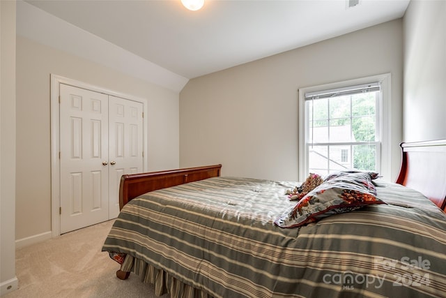 bedroom featuring lofted ceiling, light colored carpet, and a closet