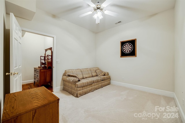 living area with light carpet and ceiling fan