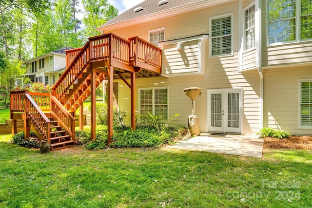 rear view of house featuring a wooden deck, a lawn, and a patio