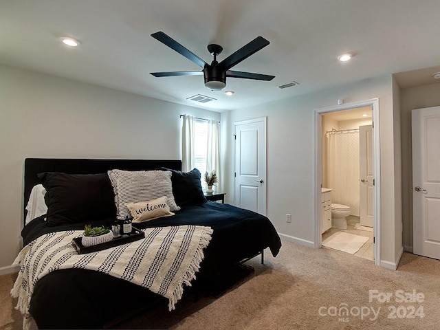 bedroom with ceiling fan, light carpet, and connected bathroom