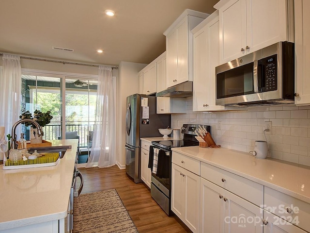 kitchen featuring wood-type flooring, sink, stainless steel appliances, and white cabinets