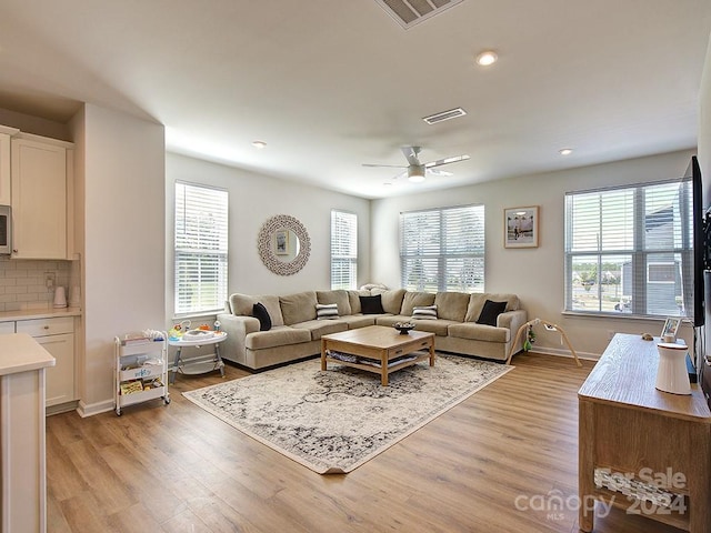 living room featuring ceiling fan, light wood-type flooring, and a wealth of natural light