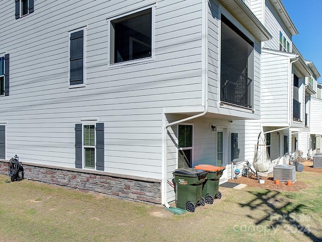 exterior space featuring central air condition unit and a lawn