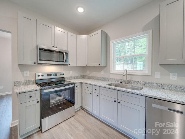 kitchen featuring light stone counters, light hardwood / wood-style floors, appliances with stainless steel finishes, and sink