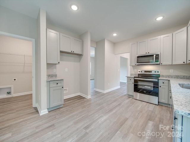 kitchen featuring light hardwood / wood-style flooring, appliances with stainless steel finishes, and light stone countertops