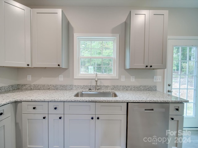 kitchen featuring dishwasher, light stone counters, plenty of natural light, and sink