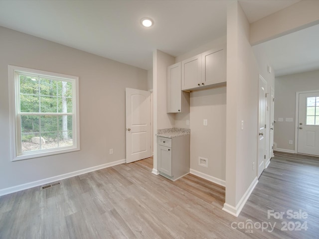 kitchen with light hardwood / wood-style floors, light stone countertops, and white cabinets