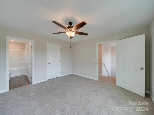 unfurnished bedroom featuring a closet, ensuite bath, ceiling fan, and light colored carpet