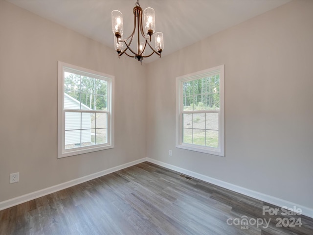 unfurnished room featuring an inviting chandelier, dark hardwood / wood-style flooring, and a wealth of natural light