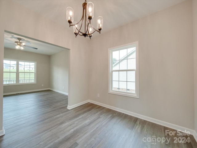 empty room with wood-type flooring and ceiling fan with notable chandelier