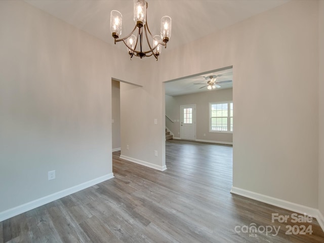 interior space with ceiling fan with notable chandelier and hardwood / wood-style flooring