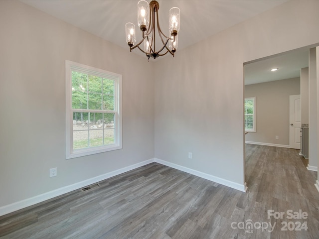 unfurnished room featuring a chandelier and hardwood / wood-style floors