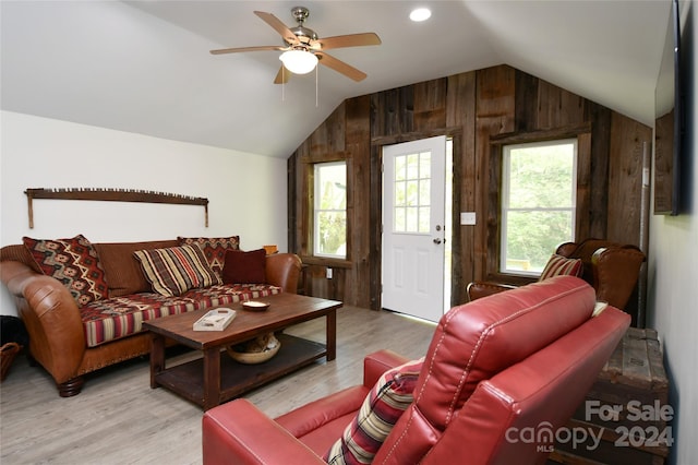 living room with vaulted ceiling, wooden walls, and hardwood / wood-style flooring