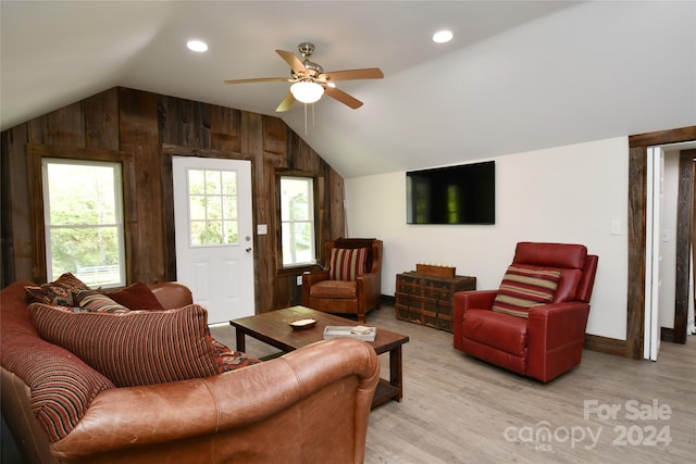 living room featuring hardwood / wood-style floors, lofted ceiling, ceiling fan, and wooden walls