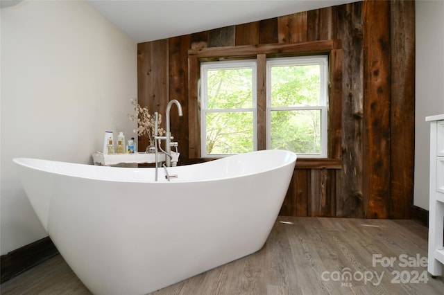 bathroom featuring hardwood / wood-style floors, wood walls, and a bath