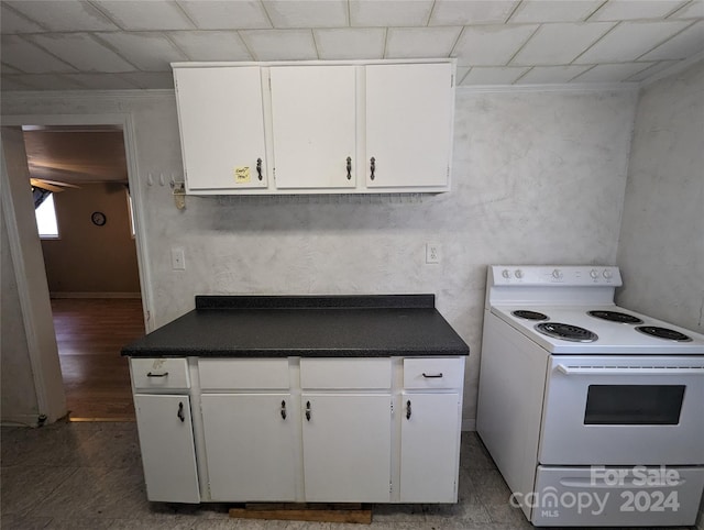 kitchen with dark tile flooring, white cabinetry, and white electric stove