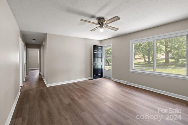 empty room featuring ceiling fan, dark hardwood / wood-style flooring, and a textured ceiling