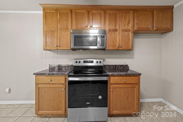 kitchen featuring appliances with stainless steel finishes, dark stone countertops, and light tile floors