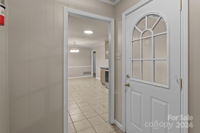 interior space with ornamental molding, an inviting chandelier, and light tile flooring