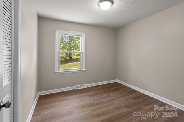 spare room featuring a textured ceiling and hardwood / wood-style floors