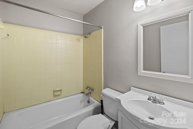 full bathroom featuring tiled shower / bath, vanity, and toilet