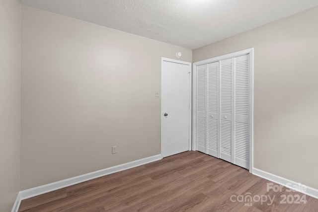 unfurnished bedroom with hardwood / wood-style floors, a closet, and a textured ceiling