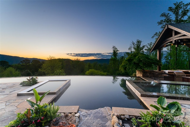 pool at dusk featuring a patio