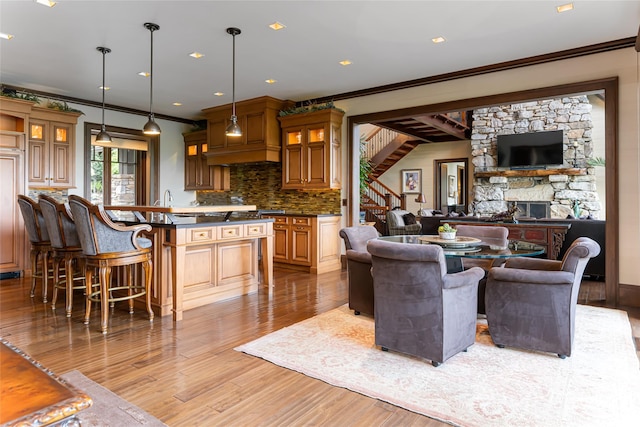 living room featuring a stone fireplace, light hardwood / wood-style floors, and ornamental molding