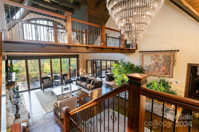 staircase featuring high vaulted ceiling, an inviting chandelier, beamed ceiling, and wood-type flooring