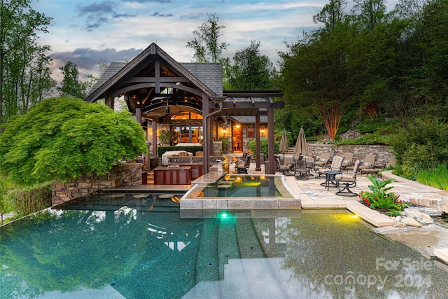 pool at dusk featuring a patio area, a bar, and a gazebo