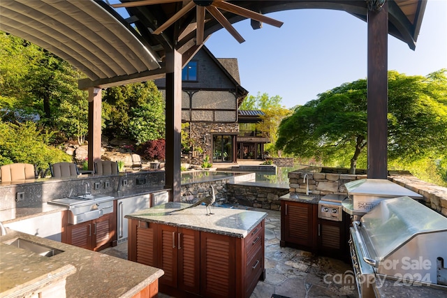 view of terrace featuring sink, ceiling fan, a grill, and exterior kitchen