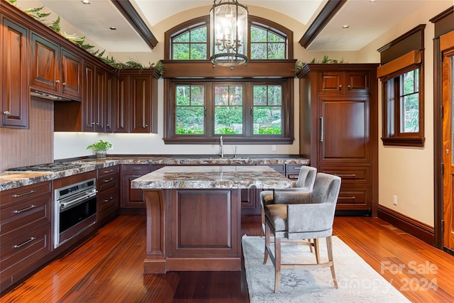 kitchen featuring a chandelier, a kitchen island, stainless steel appliances, dark wood-type flooring, and sink