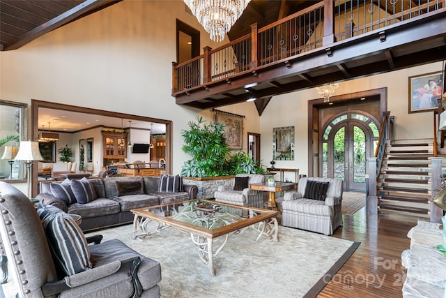 living area featuring french doors, a high ceiling, wood finished floors, a chandelier, and stairs