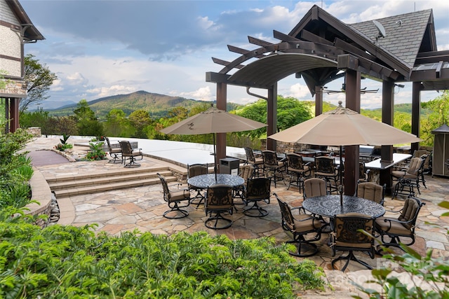 view of patio with outdoor dining area, a mountain view, and a pergola