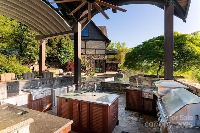 view of patio with exterior kitchen, a sink, and grilling area