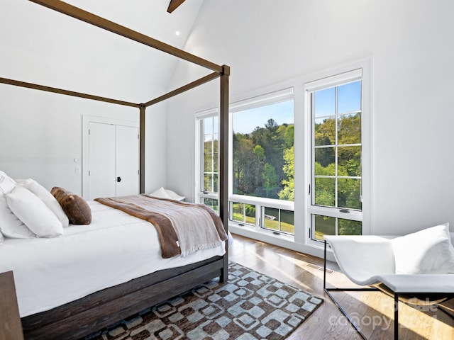 bedroom featuring visible vents, high vaulted ceiling, and wood finished floors