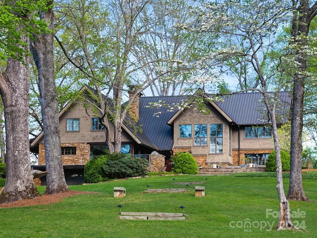 view of front facade featuring a standing seam roof, a chimney, metal roof, and a front lawn